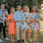 A joyful family posing together outdoors at sunset in a park.