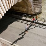 View of joggers running under the Pont de Bir-Hakeim in Paris, France during the day.